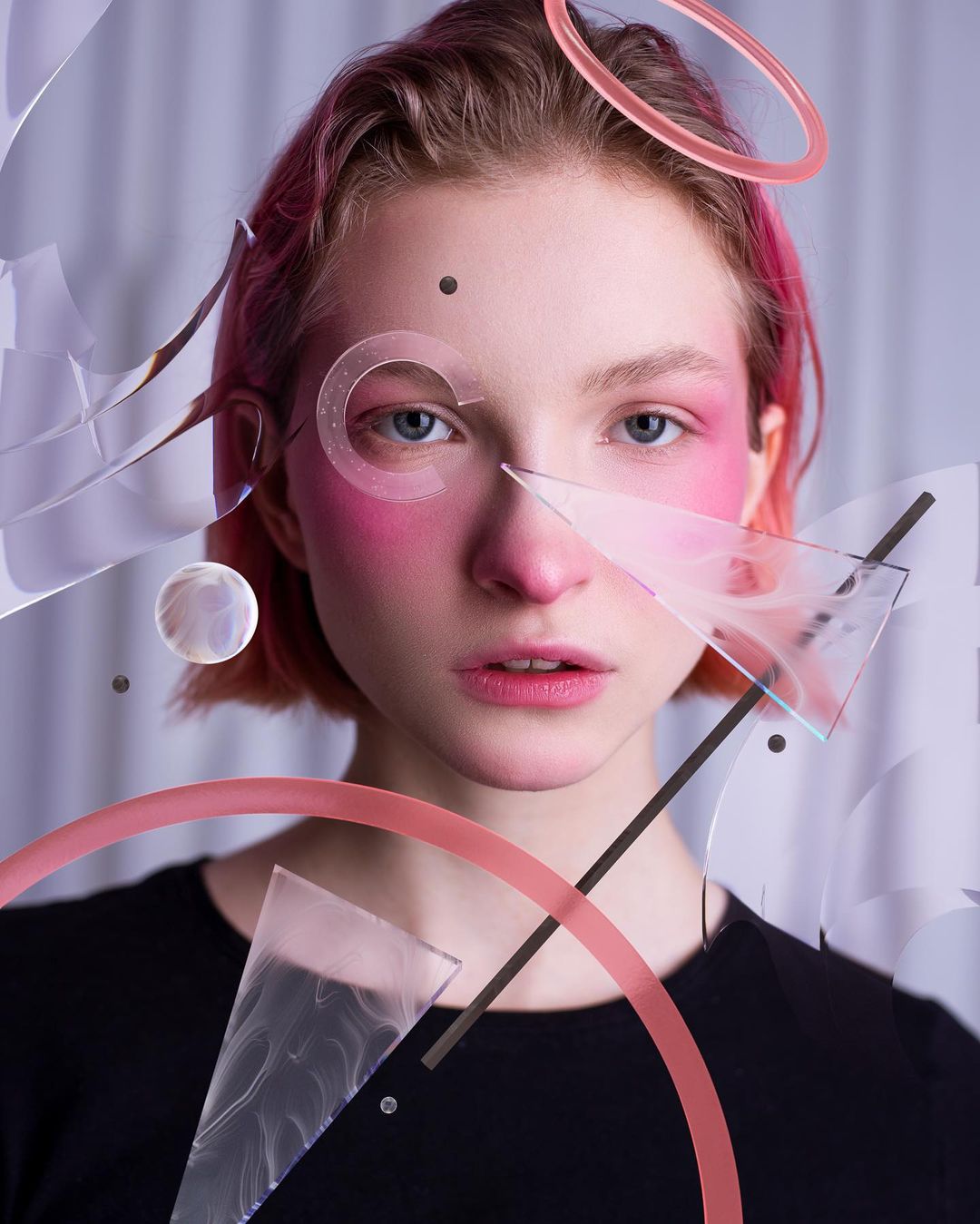 A beauty portrait: pink hair, acrylic rings and glass shards suspended across the face.